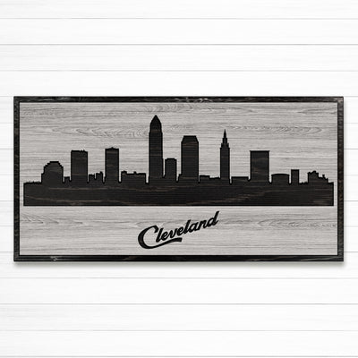 Carved wood wall art featuring the Cleveland, Ohio city skyline with detailed buildings and natural wood grain finish.