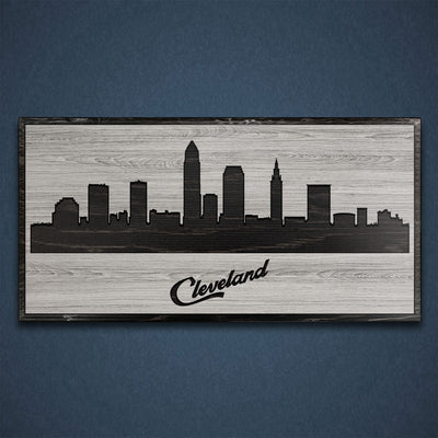 Carved wood wall art featuring the Cleveland, Ohio city skyline with detailed buildings and natural wood grain finish.