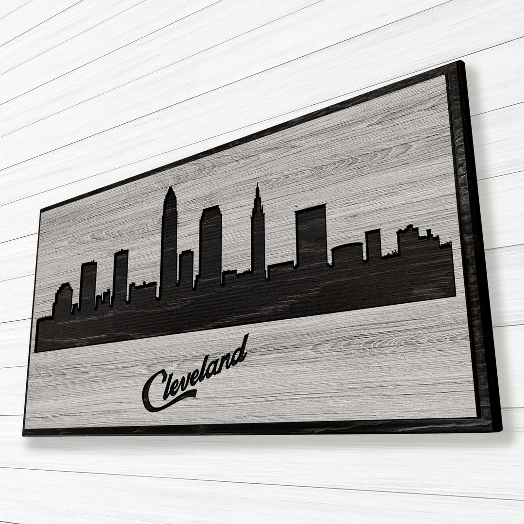 Carved wood wall art featuring the Cleveland, Ohio city skyline with detailed buildings and natural wood grain finish.