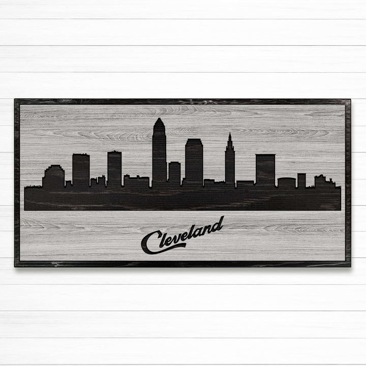 Carved wood wall art featuring the Cleveland, Ohio city skyline with detailed buildings and natural wood grain finish.